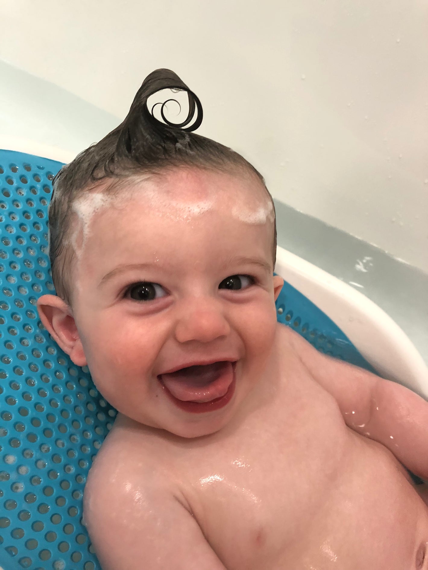 A young child stands in a bathroom wearing a diaper